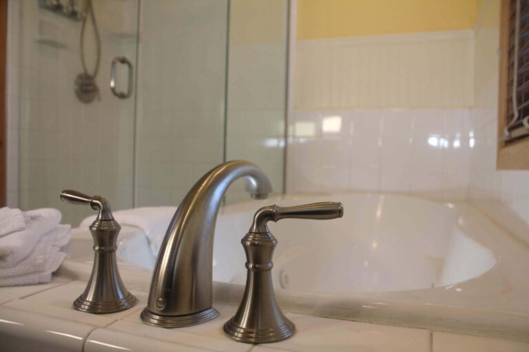 Close-up of modern chrome faucet fixtures on the tiled edge of a luxury jetted tub at Shaver Lake Inn.