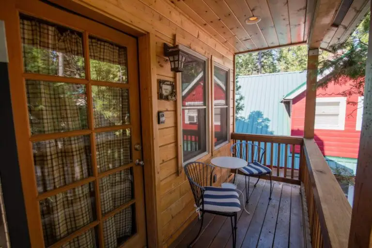 Private covered wooden balcony at the Sequoia Suite with bistro seating looking out toward Shaver Lake pines.