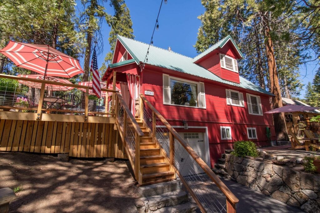 Bright exterior view of Shaver Lake Inn showing the wooden staircase leading to the sunny outdoor patio deck.