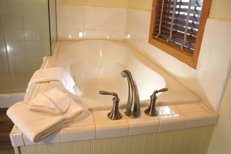 A large white jetted soaking tub with plush folded white towels at the Sequoia Suite in Shaver Lake.
