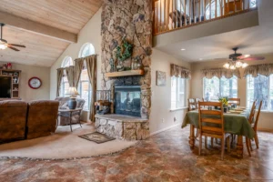 Massive floor-to-ceiling stone gas fireplace separating the living and dining rooms under vaulted ceilings at Silver Pine Lodge.
